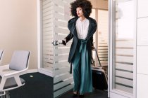 Бізнес-леді прибуває в офіс з валізою — стокове фото