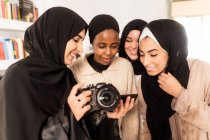 Four friends looking at photographs on camera — Stock Photo