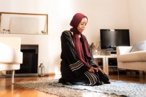 Mujer musulmana joven, arrodillada durante la oración - foto de stock