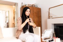 Mujer musulmana joven que se pone el pañuelo para la cabeza hijab - foto de stock
