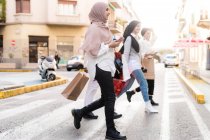 Jeunes femmes en voyage shopping, traversant la route — Photo de stock