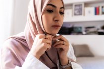 Mujer musulmana joven que se pone el pañuelo para la cabeza hijab - foto de stock