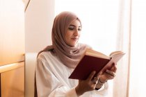 Joven mujer musulmana leyendo libro - foto de stock