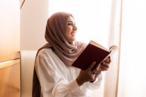 Jeune femme musulmane, lire et sourire — Photo de stock
