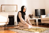 Mujer musulmana joven arrodillada en la alfombra para la oración - foto de stock
