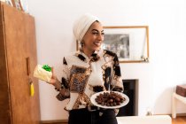 Mujer musulmana joven con plato de dátiles y un regalo - foto de stock