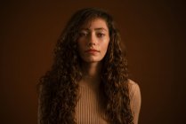 Studio portrait of young woman with long curly hair — Stock Photo