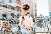 Young woman outdoors, looking at phone — Stock Photo