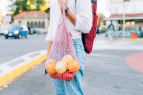 Обрезанный вид женщины, держащей струнный мешок с фруктами — стоковое фото