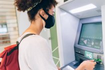 Junge Frau mit Gesichtsmaske am Geldautomaten — Stockfoto
