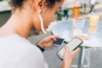 Молодая женщина использует телефон и кредитную карту в кафе на открытом воздухе — стоковое фото