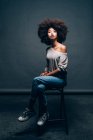 Portrait of a young woman sitting on stool — Stock Photo
