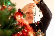 L'uomo organizza luci sull'albero di Natale — Foto stock