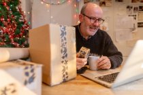 Man wrapping parcels and using laptop — Stock Photo