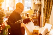 Man wrapping Christmas present to send — Stock Photo