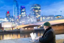 Man working on laptop by River Thames, London, UK — Stock Photo