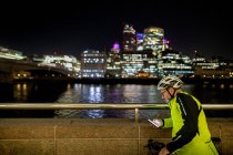 Cycliste avec téléphone dans la ville la nuit, Londres, Royaume-Uni — Photo de stock