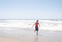 Мальчик у моря, бежит от волн — стоковое фото