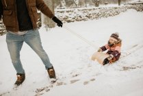 Canada, Ontario, Father pulling daughter (2-3) on toboggan — Stock Photo