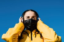 Портрет девочки-подростка (16-17 лет) в маске от гриппа и наушниках — стоковое фото