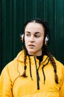 Retrato de adolescente (16-17) menina usando casaco amarelo e fones de ouvido — Fotografia de Stock