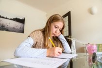 Великобритания, Суррей, девочка (10-11 лет), выполняющая домашнюю работу дома — стоковое фото