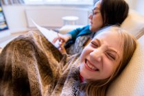 Reino Unido, Surrey, Madre e hija sonriente (10-11) en el sofá en casa - foto de stock