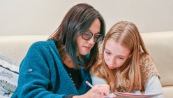 Mother helping daughter (10-11) with homework — Stock Photo