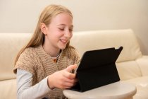 Великобритания, Surrey, Смилинг девочка (10-11 лет) с использованием цифрового планшета дома — стоковое фото