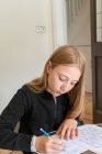 Великобритания, Суррей, девочка (10-11 лет), выполняющая домашнюю работу дома — стоковое фото