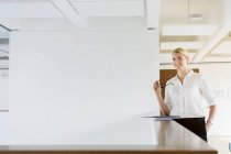 Germany, Bavaria, Munich, Portrait of young businesswoman standing in office — Stock Photo