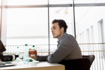 Germany, Bavaria, Munich, Young man sitting at desk in office — Stock Photo
