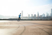 UK, London, Jogger running with downtown skyline in background — Stock Photo