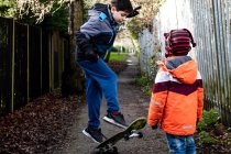Великобритания, два мальчика (4-5, 10-11), играющие на скейтборде — стоковое фото