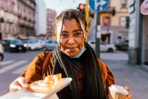 Italy, Portrait of smiling woman with snack on street — Stock Photo