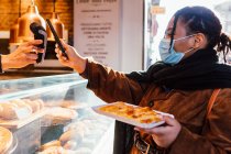Італія, Жінка в масці стоячи, платить розумним телефоном за закуску на вулиці. — стокове фото