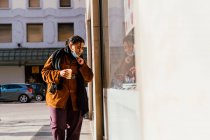 Italien, Frau mit Mundschutz und Einwegbecher blickt auf Schaufenster — Stockfoto