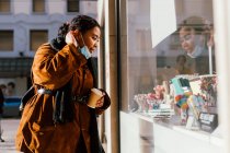 Італія, Жінка з масками обличчя і одноразовою чашею дивлячись на вікно магазину — стокове фото