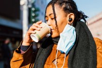 Italien, Junge Frau mit Mundschutz trinkt im Freien aus Einwegbecher — Stockfoto