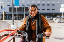 Italien, Porträt einer lächelnden jungen Frau mit Fahrrad auf der Straße der Stadt — Stockfoto