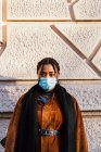 Italy, Portrait of young woman in face mask standing at wall — Stock Photo