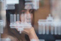 Germany, Berlin, Young woman looking through window — Stock Photo