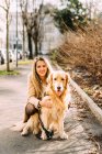 Italia, Retrato de mujer joven con perro en la acera - foto de stock