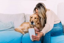 Italy, Young woman taking selfie with dog at home — Stock Photo