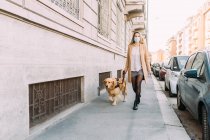 Italy, Young woman and dog walking along street — Stock Photo