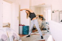 Italy, Young woman stretching at home — Stock Photo