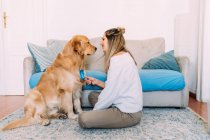 Italy, Young woman brushing dog at home — Stock Photo