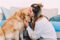 Italy, Young woman hugging dog at home — Stock Photo