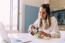 Италия, Молодая женщина пьет кофе и смотрит на ноутбук — стоковое фото