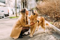 Italy, Young woman with dog on sidewalk — Stock Photo